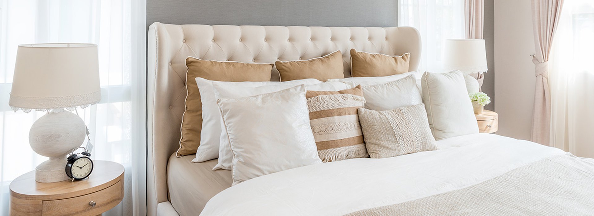 Bedroom in soft light colors. Big comfortable double bed in elegant classic bedroom